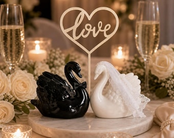 Bruidstaarttopper in de vorm van een zwaan, zwart-wit, met houten liefdesbordje