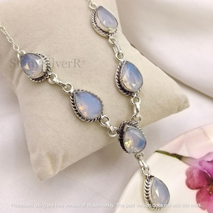 May include: A silver necklace featuring five pear-shaped, faceted iridescent stones set in twisted metal frames. The stones are connected by silver links, creating a drop-style design. The text ShinyIverR is visible on the left side of the necklace.