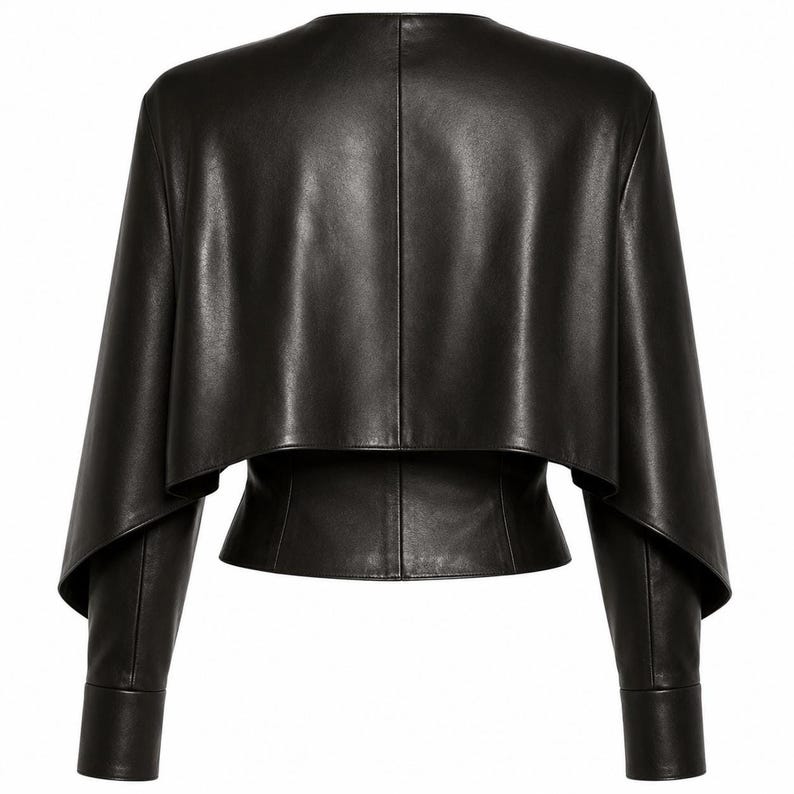 Rear view of a black genuine leather cape-style jacket with a cropped layered overlay and fitted long sleeves.