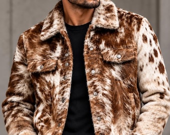 Puede incluir: Una chaqueta de piel sintética con estampado de vaca en marrón y blanco, con cuello, mangas largas, dos bolsillos en el pecho con cierre de botones y una tapeta frontal con botones. La chaqueta tiene un aspecto texturizado y peludo.