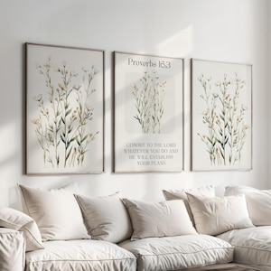 Può includere: Tre stampe da parete incorniciate con illustrazioni di fiori selvatici in stile acquerello. Le due stampe esterne mostrano composizioni floreali, mentre quella centrale include il testo Proverbs 16:3, COMMIT TO THE LORD WHATEVER YOU DO AND HE WILL ESTABLISH YOUR PLANS.