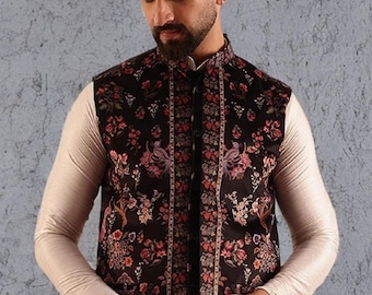 Può includere: Un gilet nero con stampa floreale, colletto alla coreana e chiusura con bottoni. Il gilet presenta un motivo floreale dettagliato nelle tonalità del rosa, del rosso e del verde. Il gilet è indossato sopra una camicia a maniche lunghe color crema.