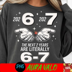 Może przedstawiać: Ciemnoszara bluza z napisem "2026-7" i "The Next 2 Years Are Literally 6-7". Projekt zawiera dwie dłonie trzymające mały prezent i gwiazdy. Na dole znajduje się czerwony baner z napisem "PNG AURA VALO".
