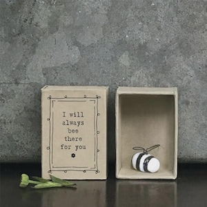 Peut inclure: Une boîte d'allumettes décorative avec le texte "I will always bee there for you" et une petite figurine d'abeille. L'abeille est blanche avec des rayures noires et se trouve à l'intérieur de la boîte d'allumettes ouverte. Une petite fleur verte est à côté.