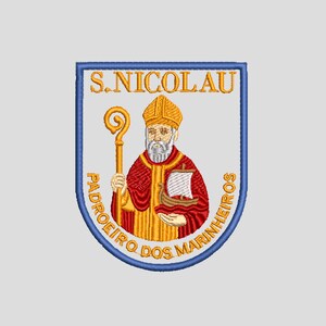 May include: Embroidered patch featuring a religious figure holding a staff and a boat. The patch is shield-shaped with a blue border and text that reads "S. NICOLAU" and "PADROEIRO DOS MARINHEIROS" in gold lettering. The figure is wearing a red robe and a gold hat.