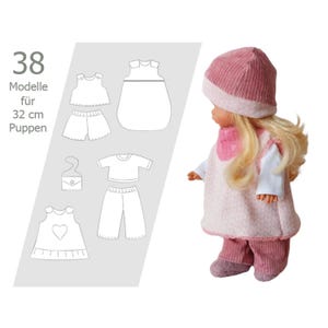 May include: A doll dressed in a pink hat, scarf, vest, trousers, and shoes. The doll has blonde hair and stands beside a diagram of doll clothing patterns. The diagram shows patterns for shorts, a dress, a shirt, and trousers. The text on the diagram reads "38 Modelle für 32 cm Puppen."
