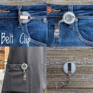 May include: A clear plastic belt clip with a retractable badge reel attached to denim jeans. The badge reel is round with a white center. The text "Belt Clip" is written in white cursive. The clip is also shown attached to a pocket.