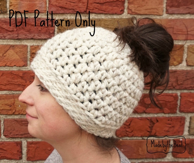 Op de afbeelding: Een witte gehaakte muts met een gat bovenop voor een paardenstaart. De muts heeft een dikke, omgeslagen rand. De tekst "PDF Pattern Only" staat bovenaan de afbeelding. De tekst "Made by the Best" staat onderaan de afbeelding.
