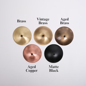 May include: Five metal discs in various finishes: Brass, Vintage Brass, Aged Brass, Aged Copper, and Matte Black. Each disc has a central hole. The text labels each finish.