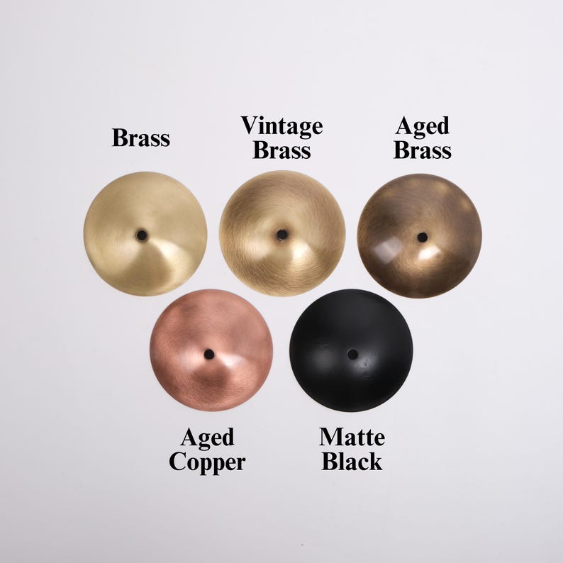 May include: Five metal discs in various finishes: Brass, Vintage Brass, Aged Brass, Aged Copper, and Matte Black. Each disc has a central hole. The text labels each finish.