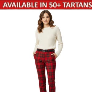 May include: A woman wearing a cream-colored sweater and red plaid pants with a black belt. The pants have a classic tartan pattern in red and green. The image includes the text "AVAILABLE IN 50+ TARTANS" in a red banner.