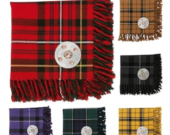 Puede incluir: Una colección de bufandas de tartán en varios colores, incluyendo rojo, negro, verde y amarillo. Cada bufanda presenta un borde con flecos y una broche plateada decorativa. El texto "AVAILABLE IN 50+ TARTANS" se muestra en la parte superior.