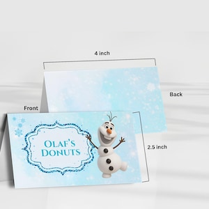 Puede incluir: Dos tarjetas de 10 cm por 6,35 cm con el tema Olaf's Donuts. La tarjeta frontal muestra un mu&ntilde;eco de nieve de dibujos animados y el texto "Olaf's Donuts" dentro de un marco de purpurina azul. El fondo es azul claro con copos de nieve.
