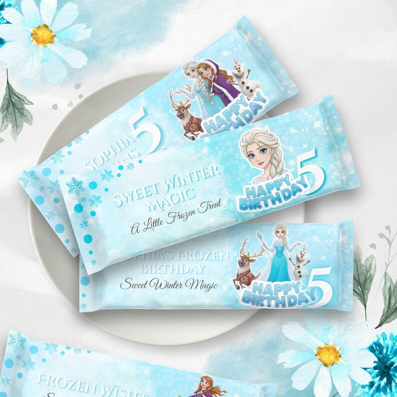 Puede incluir: Envoltorios de barras de caramelo azul claro con im&aacute;genes de Elsa, Anna, Olaf y Sven de Frozen. Los envoltorios dicen "Feliz Cumplea&ntilde;os" y "Sweet Winter Magic" con el n&uacute;mero 5. Decorados con copos de nieve.