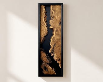 May include: A rectangular wall art piece featuring two vertical sections of natural light brown wood burl with intricate grain patterns, separated by a smooth, solid black resin river, all encased within a thin, matte black wooden frame.