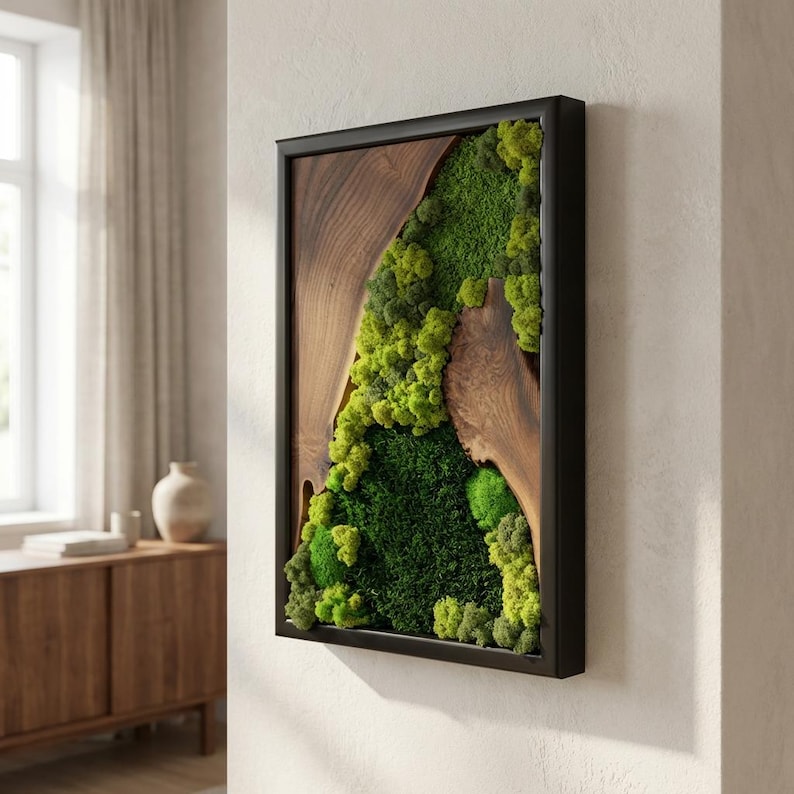 May include: Rectangular wall art featuring a natural wood grain design with a live moss arrangement. The moss is a vibrant green, framed by a black border. The wood grain is a warm brown color, creating a contrast with the green moss.