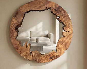 May include: A round mirror with a natural wood frame. The frame has a raw, organic edge, showcasing the wood's grain and texture. The mirror reflects a neutral-toned living room with a sofa and coffee table.