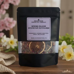 May include: A black pouch of "Spring Bloom Stovetop Potpourri" with a clear window, displaying dried orange slices and botanicals. The label lists ingredients: lavender, rose petal, lemon, lime, and orange. The package is from Brandywine Simmer Pot Company.