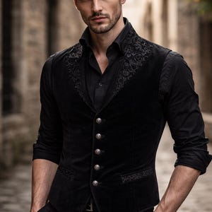 Pode incluir: Um colete de veludo preto com bordados ornamentados na gola e nas bordas, combinado com uma camisa preta. O colete apresenta botões prateados. O estilo é de inspiração gótica ou vitoriana.