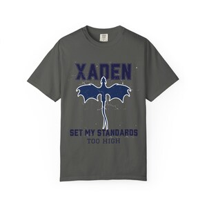 White Comfort Colors tee flat lay Xaden navy dragon graphic tied knot on white bedding, label visible