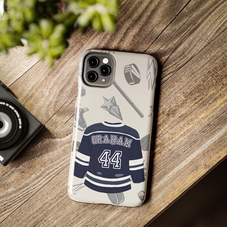 Cream iPhone 11 Pro Graham 44 navy hockey jersey case flat lay on wooden surface with camera