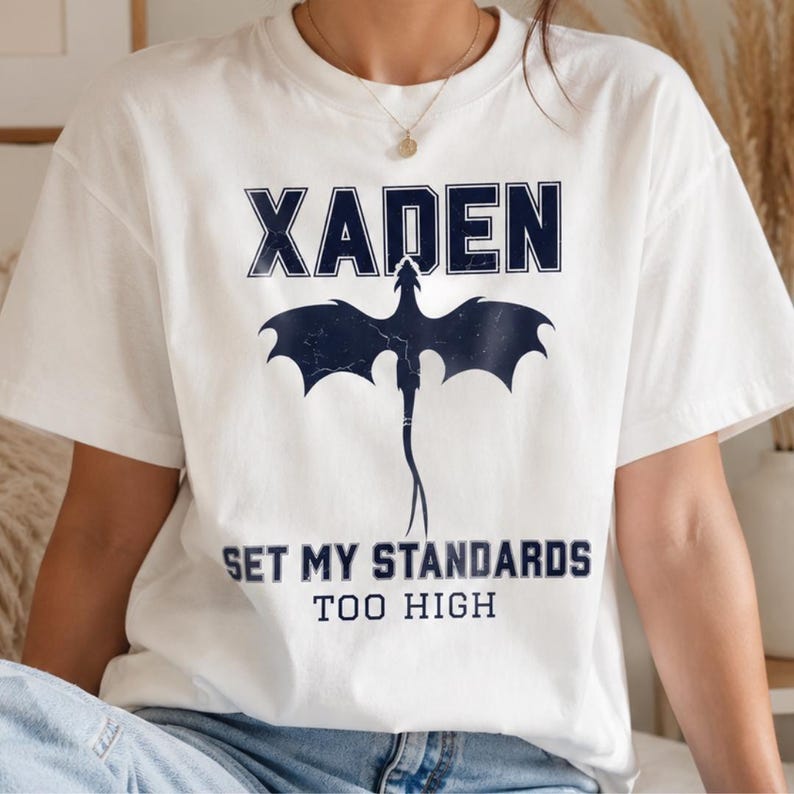 Woman in Xaden Riorson fantasy white tshirt seated on bed - bookish gift for her- romantasy shirt- enemies to lovers merch