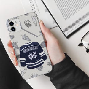 Off Campus phone case cream iPhone 11 Graham 44 navy jersey held in one hand open book and glasses desk