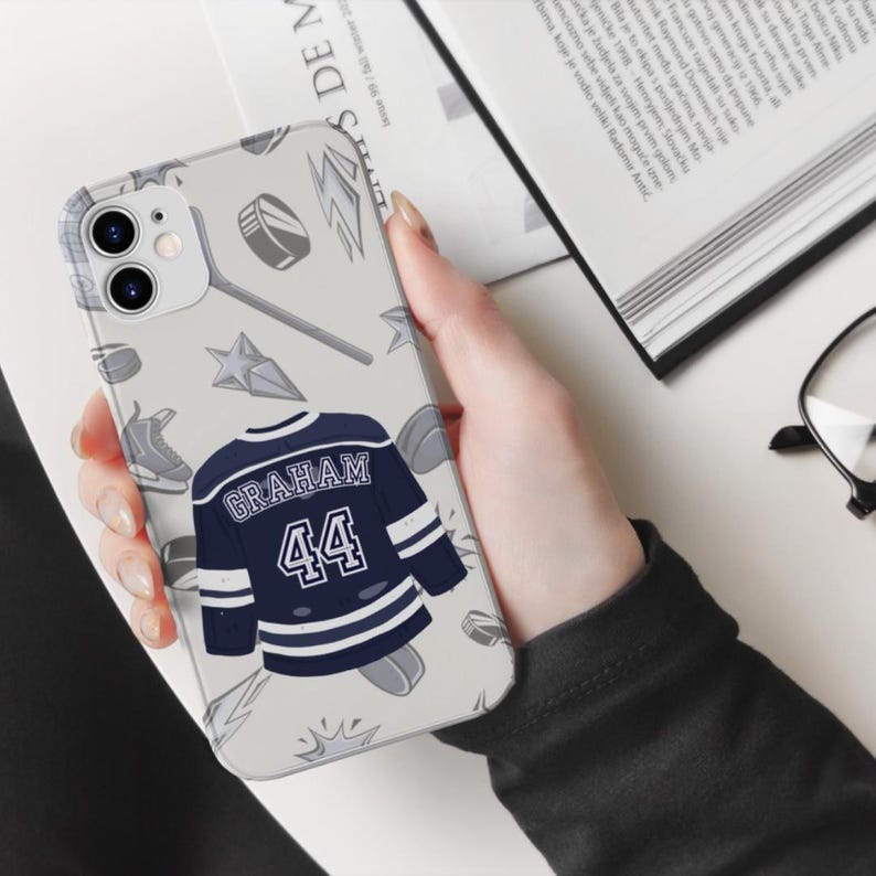 Off Campus phone case cream iPhone 11 Graham 44 navy jersey held in one hand open book and glasses desk