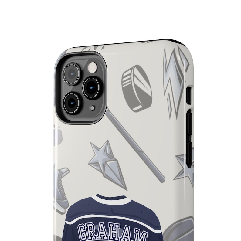 Cream iPhone 11 Pro Graham 44 hockey jersey case angled close-up showing puck stick lightning bolt pattern detail