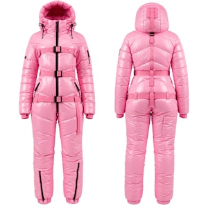 Puede incluir: Un traje de nieve aislado de color rosa brillante y acabado lustroso, con capucha, cremallera central negra y tres correas horizontales con hebilla en la parte delantera. La prenda incluye mangas largas, piernas con cremalleras negras en los tobillos y un sistema de correas con hebilla a juego en la espalda.