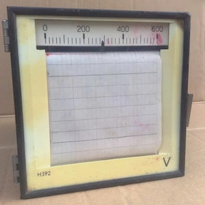 Könnte beinhalten: Vintage elektrisches Messgerät mit schwarzem Rahmen und gelbem Innenraum. Das Messgerät hat eine Skala von 0 bis 600, ein Papierdiagramm und die Nummer "H392" unten. Wahrscheinlich zur Messung der Spannung verwendet.