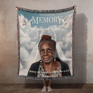 May include: A woven throw blanket featuring a memorial design with the text IN LOVING MEMORY, Emily Carter, 1958-2024, and Nothing can separate us from the love of God Romans 8:38-39. The image shows a portrait, white doves, and a stairway to clouds.