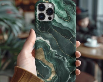 May include: A smartphone case with a green marble design. The case has a swirling pattern of dark green and gold, with a glossy finish. The case has a camera cutout and is held in a person's hand.