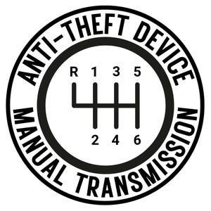 May include: A black and white circular graphic with the words "ANTI-THEFT DEVICE MANUAL TRANSMISSION" encircling a gear shift pattern. The gear shift shows R, 1, 2, 3, 4, 5, and 6.