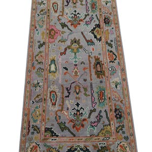 May include: A rectangular, hand-knotted rug with a gray field and a detailed border. The rug features a central design with floral and geometric motifs in shades of pink, green, orange, and blue. The border is a darker shade of gray.
