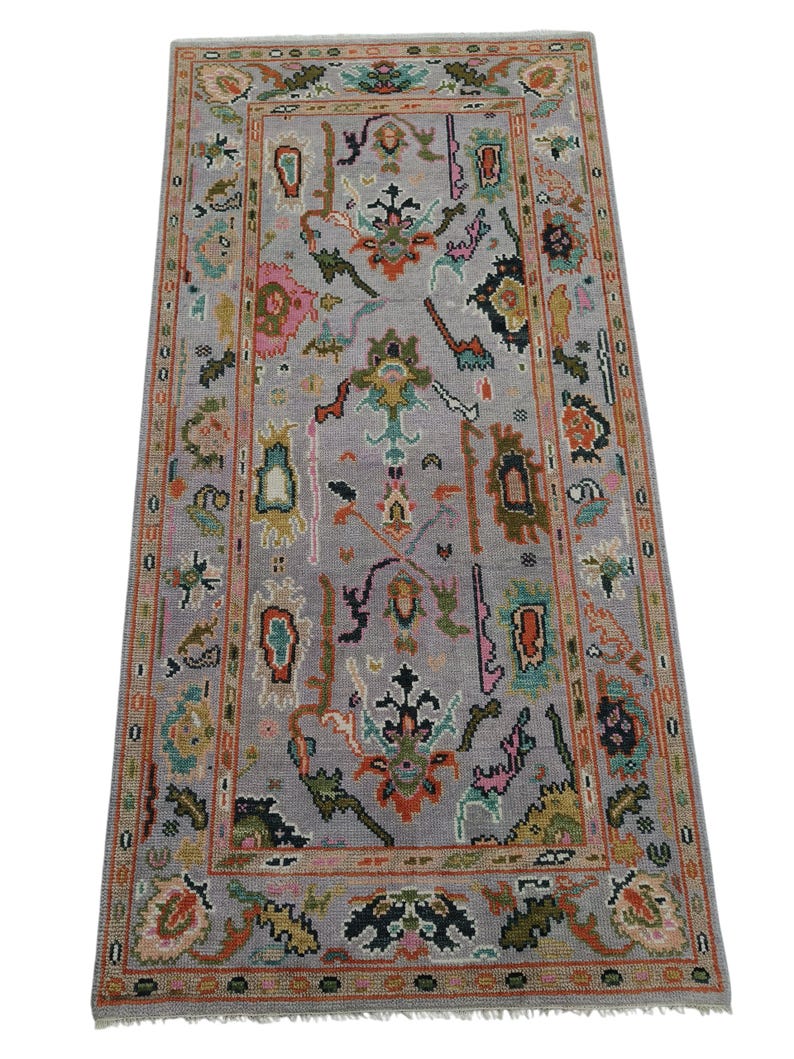 May include: A rectangular, hand-knotted rug with a gray field and a detailed border. The rug features a central design with floral and geometric motifs in shades of pink, green, orange, and blue. The border is a darker shade of gray.