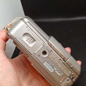 以下が含まれることがあります： シルバーのオリンパスC-50ズームデジタルカメラ。カメラはシルバーのボディで、「OLYMPUS OPTICAL CO., LTD. DIGITAL CAMERA MODEL NO. C-50 ZOOM DC 4.8V」と書かれたラベルが付いています。カメラは手で持たれています。