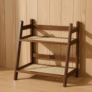 May include: A two-tiered, dark brown wooden shelf with woven rattan shelves. The frame has an A-frame design on the sides, and the shelves are rectangular. The shelf is set against a light brown wooden wall.