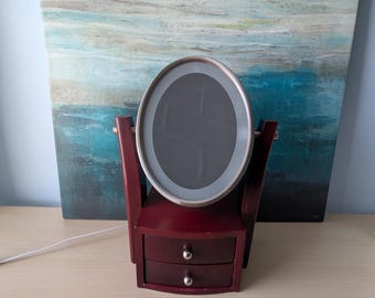 Coiffeuse vintage en bois de couleur acajou avec 2 tiroirs, miroir pivotant et éclairage.