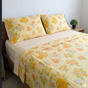 Set di lenzuola matrimoniali vintage anni '70: lenzuolo piatto con stampa floreale retrò e lenzuolo con angoli beige; un arredamento nostalgico per la camera da letto.