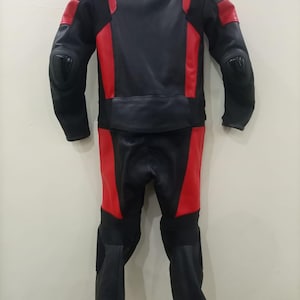 May include: Black and red motorcycle racing suit. The suit is made of leather and features red panels on the shoulders, arms, and legs. The suit has protective padding on the elbows and knees. The suit is designed for safety and performance.