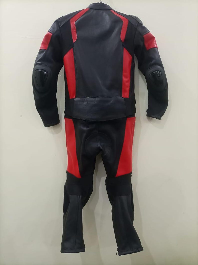 May include: Black and red motorcycle racing suit. The suit is made of leather and features red panels on the shoulders, arms, and legs. The suit has protective padding on the elbows and knees. The suit is designed for safety and performance.