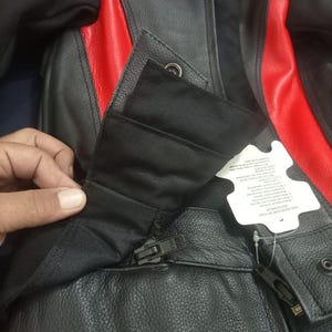 May include: Black and red leather motorcycle jacket with a zipper closure and snap details. The jacket features red panels on the shoulders and sides. The jacket has a tag attached.