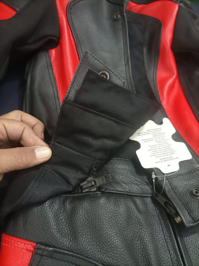 May include: Black and red leather motorcycle jacket with a zipper closure and snap details. The jacket features red panels on the shoulders and sides. The jacket has a tag attached.