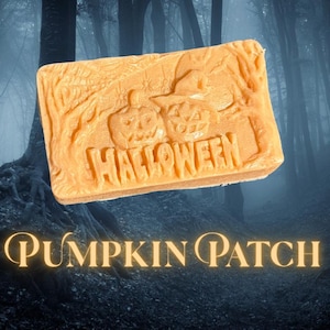 Puede incluir: Una pastilla de jabón rectangular de color naranja con un diseño en relieve de dos calabazas, un sombrero de bruja y árboles, con la palabra HALLOWEEN tallada en la superficie. El texto PUMPKIN PATCH aparece debajo en letra serif.