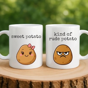 May include: Two white ceramic mugs with black text and potato illustrations. One mug says "sweet potato" with a smiling potato wearing a pink bow. The other mug says "kind of rude potato" with an angry potato.