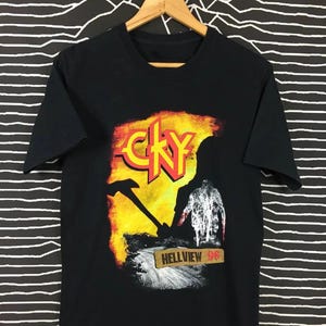 May include: Black t-shirt featuring a graphic design with the word "CKY" in yellow and red, set against a fiery background. The design includes a silhouette and the text "HELLVIEW 96".
