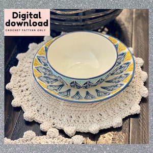 Könnte beinhalten: Ein gehäkeltes Platzset mit einem gewellten Rand und einer Schüssel und einem Teller darauf. Der Teller hat ein blaues, gelbes und weißes Muster. Die Schüssel ist weiß mit einem blauen und grünen Rand.