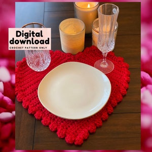 May include: A red, heart-shaped crochet placemat with a scalloped edge, holding a white plate with a gold rim. The image includes a glass, a champagne flute, and lit candles. Text on the left reads "Digital download CROCHET PATTERN ONLY."