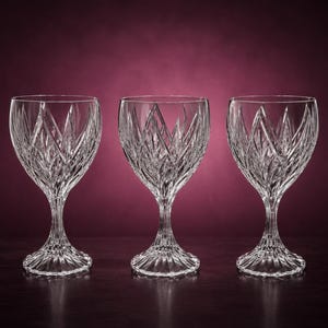 May include: Three clear crystal wine glasses featuring a deep, intricate diamond and vertical cut pattern on the bowls. Each glass has a short, faceted stem and a wide, circular base with radiating lines extending from the centre to the edge.